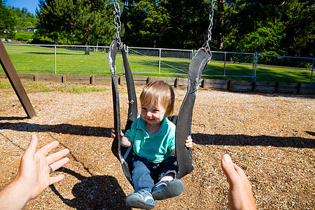 男孩在摇摆赛孩子父亲孩子们男生秋千男人微笑公园操场乐趣图片