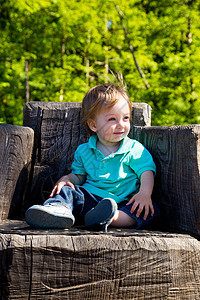 男孩坐在跳板椅子上树桩儿子孩子公园儿童乐趣座位木头操场衬衫图片