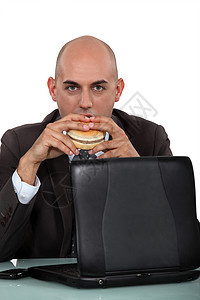 商务人士在书桌上吃汉堡包夹克零食人士笔记本商务衬衫办公室午餐工作室食物图片