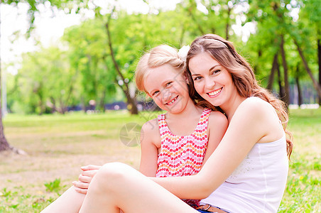 母亲和女儿一起坐在草地上女孩地面放松场地公园花园生活婴儿父母成人图片