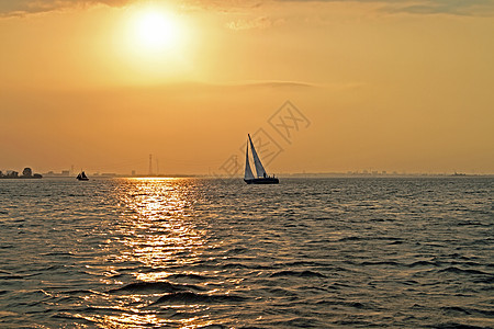 日落时在荷兰IJsselmeer号上航行游艇男人女士运输风帆男性运动帆船图片