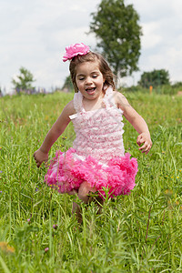 穿粉红裙子的小女孩跑在草地上花朵戏剧幸福太阳能日光假期女孩乐趣风光情绪图片