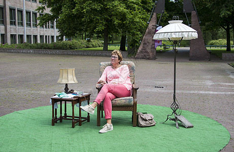 坐在有桌和灯的椅子上的公园里的妇女图片