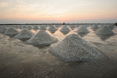 泰国海岸农村地区盐池里的盐堆里有盐农民培育工作天空勘探日落池塘少校热带订金图片