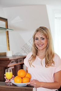 用新鲜橙子向健康女人微笑图片