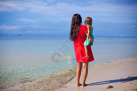 母亲和小女儿的背视望着大海海滨妈妈假期情调热带海滩女孩家庭海洋乐趣图片