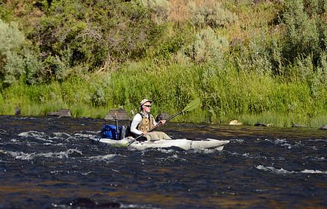 一个男人独自一人在河上 一条皮艇钓鱼图片
