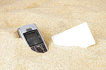 在沙沙中挂有名片的移动电话图片