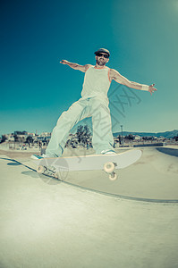 混凝土池中的滑板机危险树木水池城市滑板男人太阳牛仔裤栏杆运动图片