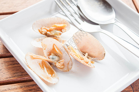 用勺子在白盘上炒烤辣椒酱蛤蜊图片