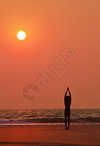 在海洋日落时的瑜伽练习 男人休眠图片