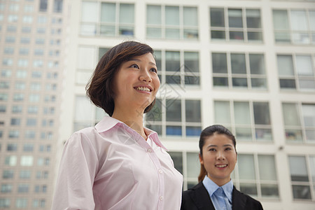 站在 生物多样性公约 外的青年商业妇女 肖像人士黑发两个人团结摄影商务天空服装同事业务图片