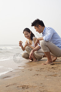 看着海边贝壳的年轻夫妇 中国水域边缘短发海滩目的地勘探休闲旅行摄影服装微笑旅游图片