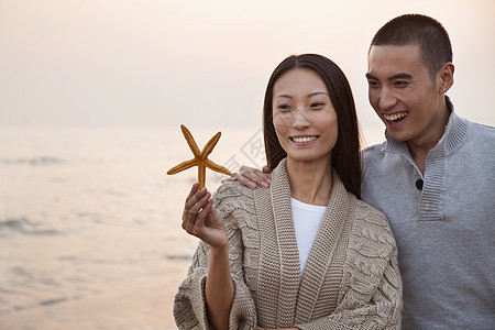 环贝壳的年轻夫妇毛衣团结海星目的地旅游海滩海洋男朋友女性沉思图片