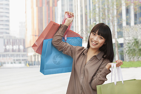 北京市外持有购物袋的青年妇女肖像露齿购物服装外观黑发零售衬衫摄影蓝色乐趣图片
