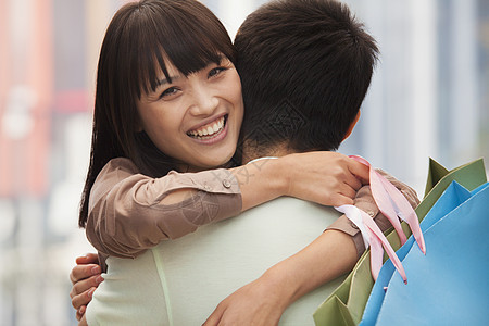 年轻夫妇用购物袋拥抱小夫妻 户外 北京幸福短发零售购物女性服装长发露齿年轻人黑发图片
