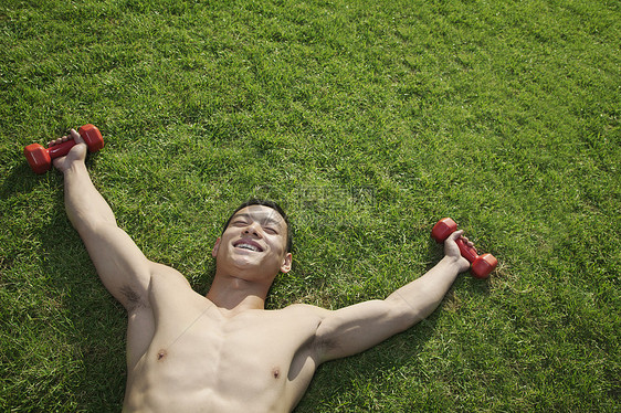 在北京和哑铃一起在草地里躺着的不穿衣服的人摄影年轻人力量能力运动膀子运动员享受微笑红色图片
