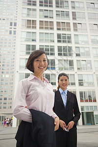 站在 生物多样性公约 外的青年商业妇女 肖像两个人团结前景城市天空衬衫同事建筑收腰摄影图片