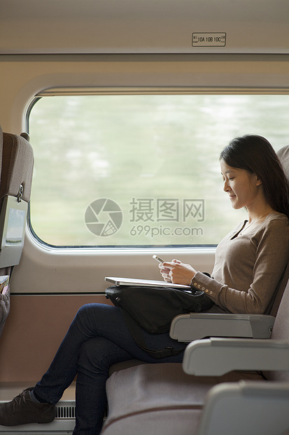 坐在火车上使用手机的年轻女子图片