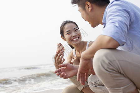 看着海边贝壳的年轻夫妇 中国水域边缘倾斜黑发微笑年轻人旅游享受假期短发女朋友团结图片