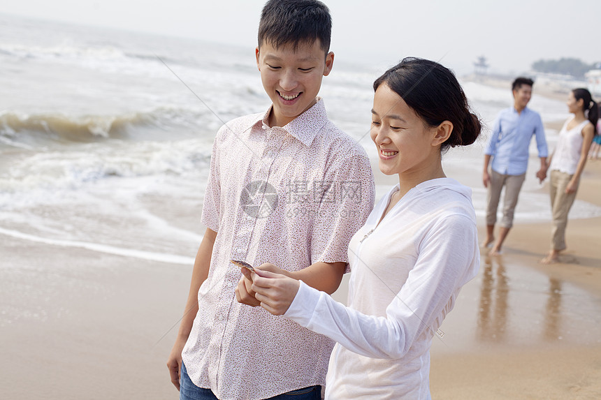 年轻夫妇站在中国海滩的贝壳上观望着图片