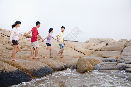 四位朋友在海边的岩石上行走摄影休闲假期微笑旅行服装享受友谊海滩自由图片