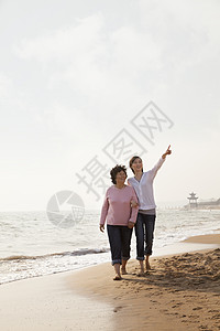 祖母和外孙女在海滩边走散步海洋活力老年家庭旅游幸福赤脚旅行感情微笑图片