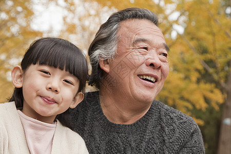 爷爷和孙女在公园里树区保暖快乐白发活动休闲季节女孩们幸福童年图片