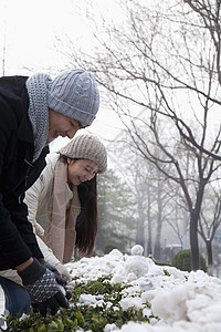 情侣在雪中玩耍弯曲乐趣年轻人享受围巾针织帽女朋友投掷服装活动图片