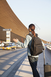 在机场搭乘出租车的年轻旅行者航班日落机动性休闲商业马尾辫服装旅游摄影棕色图片