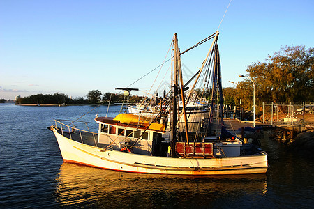 日落时的拖网鼠索具外表蓝色桅杆船体小艇船只地平线全景远景图片