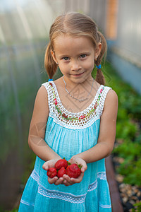 花园里可爱小女孩的肖像 手拿着浆果的花朵图片
