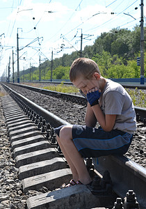 坐在铁轨上的十几岁男孩的肖像年轻人关系铁路交叉罪行少年图片