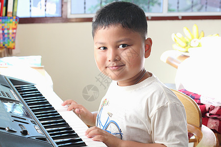 小男孩弹钢琴好玩喜悦男生童年排演键盘衣服孩子音乐合成器音乐家图片