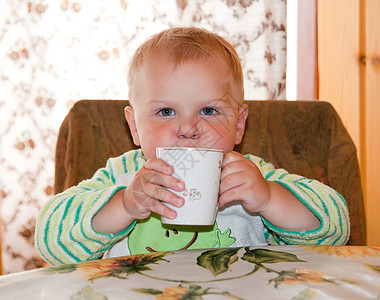 小男孩在桌边喝酒桌子微笑男孩们婴儿果汁甜点厨房杯子牛奶食物图片
