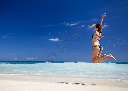 女人在海滩上跳跃太阳天堂成功喜悦旅行天空跑步游泳衣身体自由图片