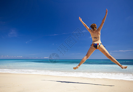 女人在海滩上跳跃旅行跑步幸福女性天堂热带蓝色成功闲暇喜悦图片