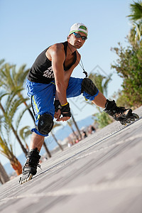 夏季户外穿着内滑鞋的青年男子太阳溜冰者诡计沥青成人男性晴天闲暇轮子蓝色图片