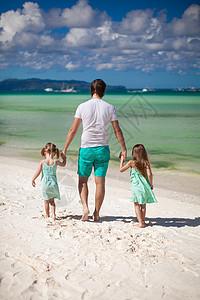 父亲和两个可爱女儿在白沙滩上行走的近视海岸婴儿幸福成人男人热带异国家庭海洋父母图片