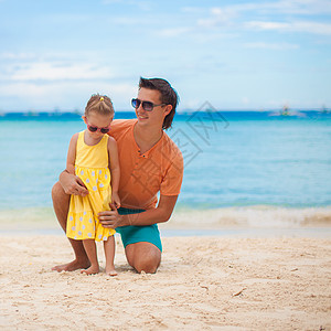 快乐的父亲和他可爱的小女儿 在白沙上图片