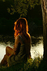 女孩坐在森林河岸上的女孩银行女性农村树木女士草地国家娱乐乡村假期图片