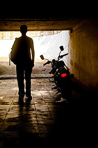 摩托车附近黑暗隧道中的车手图片