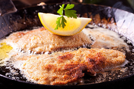 在锅里煎炸鸡肉饼烹饪气泡盘子油炸香菜牛扒牛肉柠檬美食面包屑图片