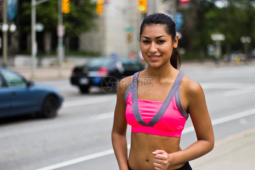合适的年轻女子在繁忙的街道上奔跑速度耐力活力赛跑者文胸慢跑者福利训练女孩娱乐图片