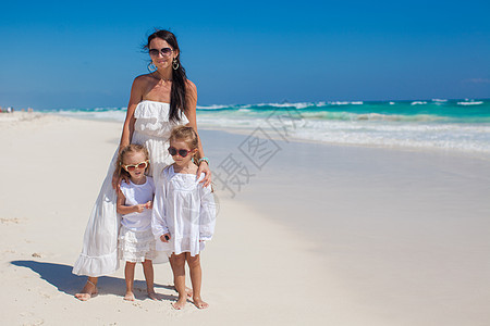 年轻母亲和两个时尚小孩 在阳光明日的奇异海滩上假期异国孩子海滨海岸线女性妈妈成人晴天情调图片