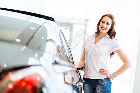 站在汽车旁边的年轻妇女驾驶机械蓝色车库引擎女性职业推销员男性经销商图片