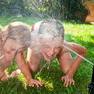 儿童在夏季花园玩耍孩子们男生乐趣活动洒水器草地快乐微笑孩子情感图片