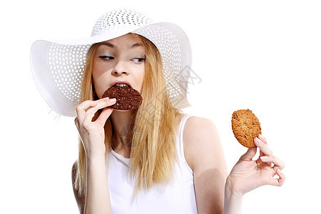 可爱的年轻女人在白背景上吃饼干帽子食物甜点垃圾巧克力小吃乐趣女孩微笑成人图片