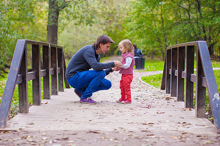 年轻父亲和他的小女儿在秋天公园散步图片