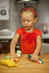 小女孩在厨房里用水果蔬菜和水果玩耍游戏帮手桌子女性早餐时间厨师衣服厚脸午餐图片